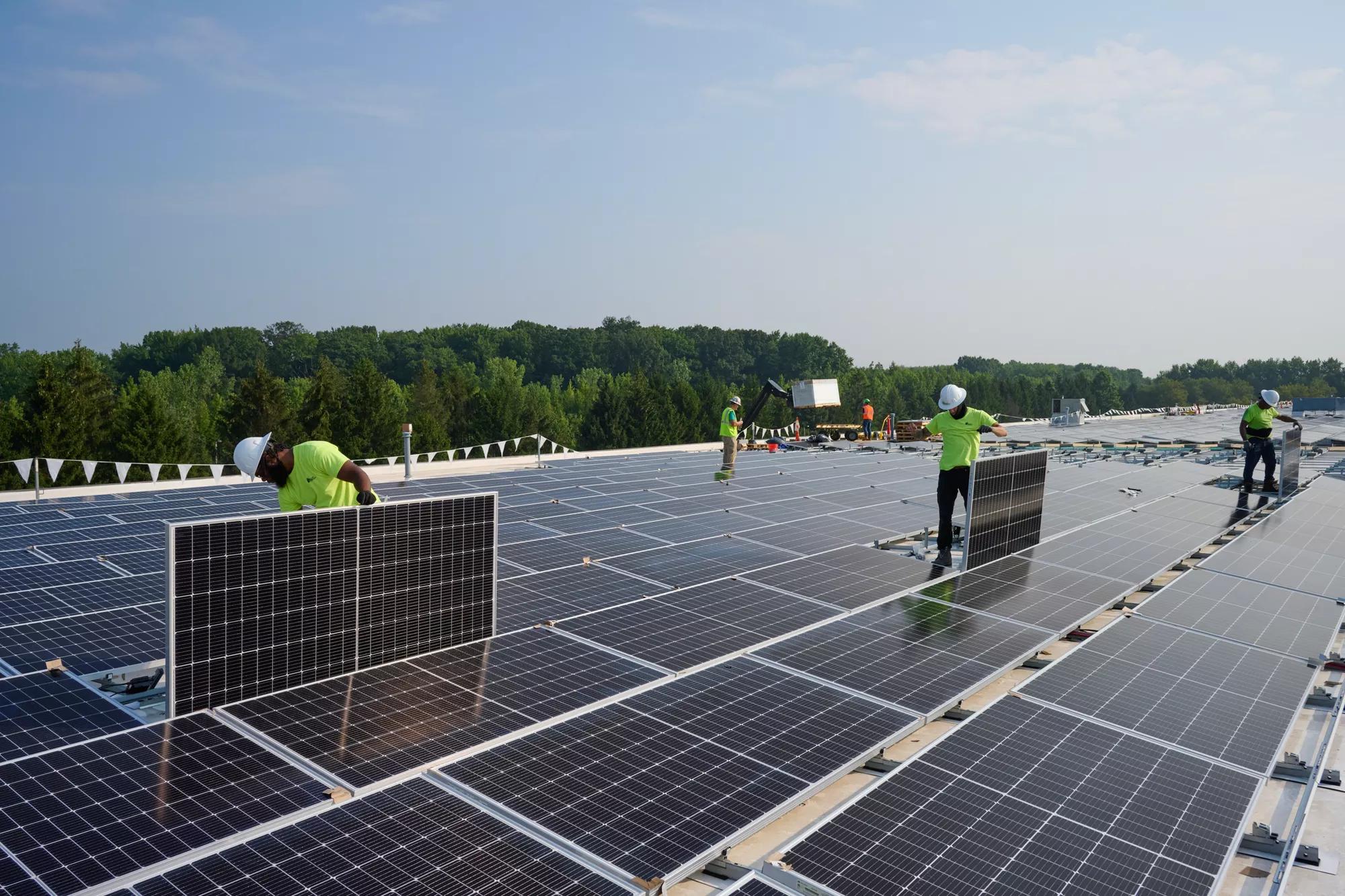 Workers installing solar panels on the roof of a Link Logistics industrial warehouse in Trenton, NJ